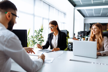 Business professionals. Group of young confident business people working together in the office at the table with a laptop, business concept