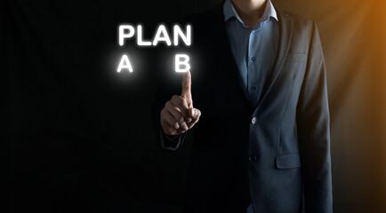 Businessman in a suit chooses options for plan development, Plan A, Plan B. on virtual screen. Business strategy, choosing a plan or decision concept.