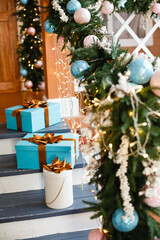 Christmas presents/gifts on home terrace under fir-tree. Vintage New Year decorations near a house on stairs. Gift boxes and lantern under fir-tree. Christmas mood. Celebrating of New Year