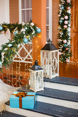 Christmas presents/gifts on home terrace under fir-tree. Vintage New Year decorations near a house on stairs. Gift boxes and lantern under fir-tree. Christmas mood. Celebrating of New Year