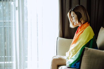 Asian girl and rainbow flag, Young lesbian sit alone in living room.