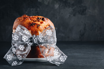 Panettone cake. Traditional Italian Christmas cake with dried fruits on dark stone background