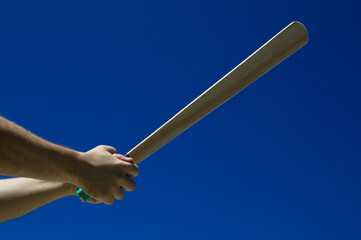 Fototapeta premium Taco de madeira com fundo do céu azul na mão de uma jogador