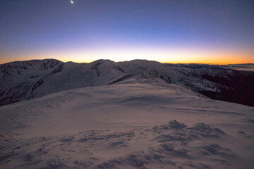 The horizon illuminates the last light of the sunset and in the sky I show the first stars in the snowy mountain landscape