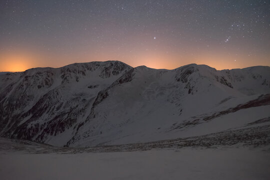 Winter landscape in a mountainous environment in the dark under a night sky full of stars