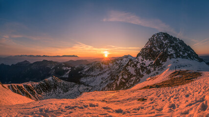 Sunrise in high mountain environment with snow and soft clouds in the sky