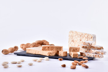 Traditional spanish nougat on a slate plate with an assortment of almonds on a light background....