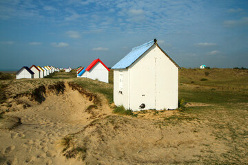 The tiny white beach cottages with colorful roofs at a beach by Gouville-sur-Mer in France in Normandy. The attraction for the tourists. 