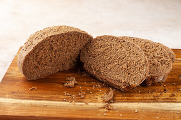 Close-up fresh chopped brown rye bread, slices on wooden cutting board