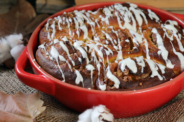 Pumpkin Cinnamon Rolls. Pumpkin buns with nuts and cinnamon, against the background of old books and yellow leaves.