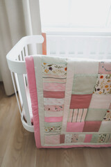Cozy baby cot with pink patchwork blanket.  Bedding and textile for children nursery. Nap and sleep time