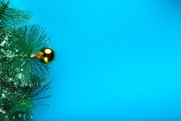 Obraz premium Pine twig in the snow with a ball decoration on a blue background.