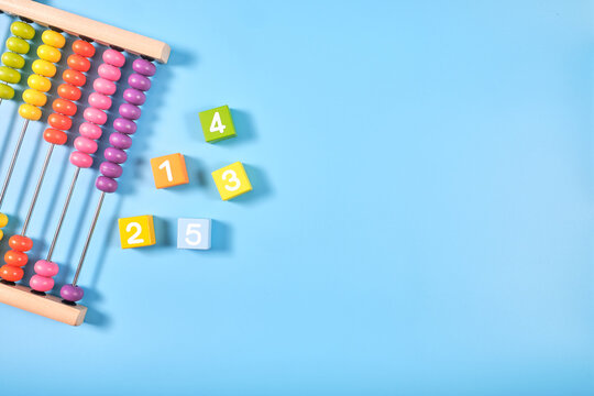 Flat lay, Top view of wooden bricks and abacus toy background with copy space for text, Numeral cubes with numbers 1 to 5 and colorful abacus,  Math concept