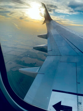 View from airplane window and the wing with sunset sky over fluffy clouds, flying and traveling concept background