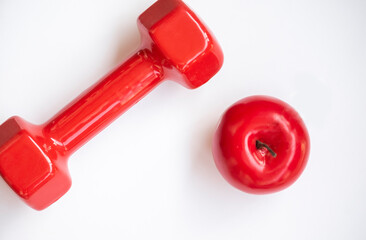 Red sport dumbbell and apple on the white background.