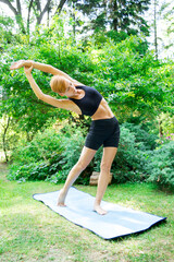 woman doing yoga in the park, young girl doing various wellness exercises, the concept of a healthy...
