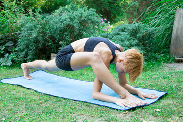 woman doing yoga in the park, young girl doing various wellness exercises, the concept of a healthy...