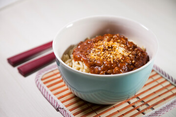 Spaghetti pasta with tomato sauce in white and blue bowl, white wooden background and resting straw plate and cutlery on the side, Brazilian cuisine copy space, top view. Food concept. Pasta concept.