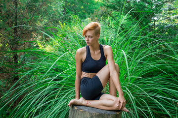 woman doing yoga in the park, young girl doing various wellness exercises, the concept of a healthy...