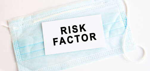 White card with the inscription RISK FACTOR a medical protective mask. Medical concept.