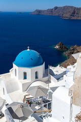 Fototapeta na wymiar Beautiful view of Oia town in Santorini island with old whitewashed houses and typical blue domes of orthodox churches, Greece. Greek landscape on a sunny day