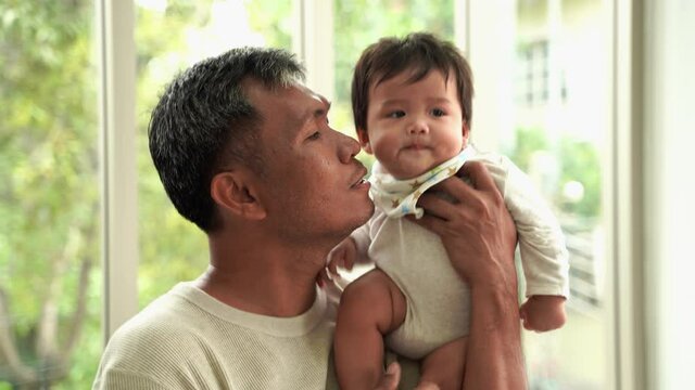 Grandfather holding grandson and kissing on the cheek, Asian family
