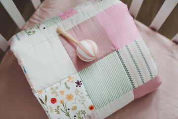Cozy baby cot with pink patchwork blanket.  Bedding and textile for children nursery. Nap and sleep...