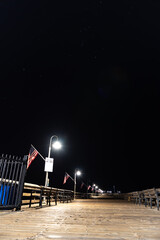 Pier lamps illuminate the Ventura Pier wooden walkway under Orion and other star constellations in...