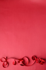 Red ribbon for presents or surprises for Christmas, new year, Valentine's day, international women's day or for celebrating holidays on a red background wity copy space.