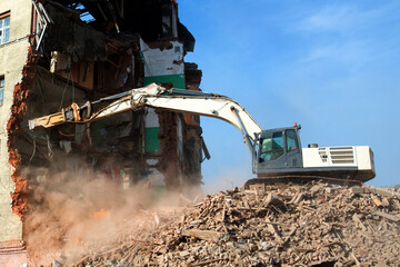 Dismantling of an old factory by backhoe breaking concrete structure of industrial building in the...