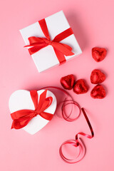 Top view ofwhite gift boxes with red ribbon, presents or surprises for Valentine's day, international women's day or for celebrating holidays on  pink background copy space.