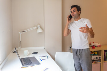 businessman standing with his mobile phone working at home in home clothes while answering messages