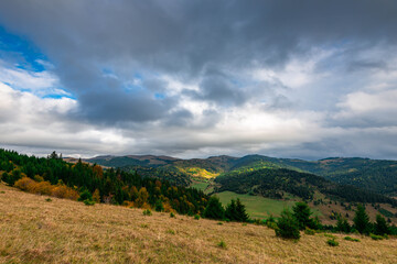 Fototapeta na wymiar Gathering storm clouds over autumn forest in the Carpathian mountains, sunrays painting the beautiful scene.
