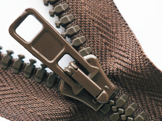 Brown zipper slider very close-up on a white background. Not isolated. Sewing production, home...