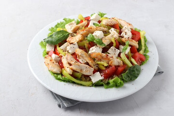 Salad with bulgur, baked chicken, bell pepper, basil and feta on a white plate, Closeup