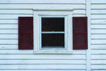 Obraz na płótnie Canvas Old window with shutters on a white wooden facade