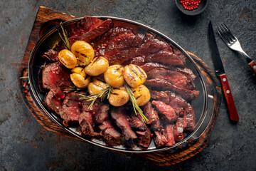 Hot Mix of grilled steaks on a plate with potatoes and rosemary, top view