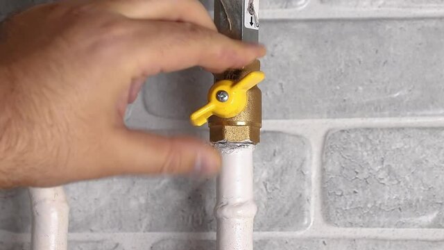 hand of a man close yellow plumbing or gas valve at home