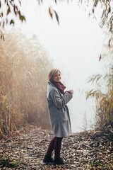 A girl runs along the shore of the lake in a foggy morning. She is having fun and has a good mood