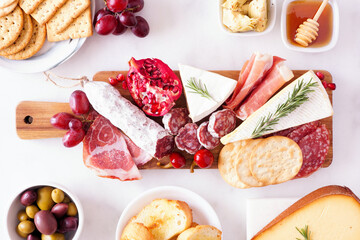 Charcuterie board of assorted cheeses, meats and appetizers. Top view table scene on a white marble...