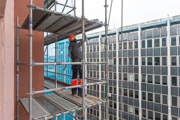 obrero de la construcción colocando un andamio de obra para reparar una fachada 