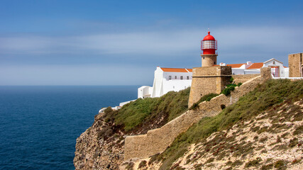 Fototapeta na wymiar Red lighthouse overlooking the sea at Cabo San Vicente in Sagres, Portuguese Algarve