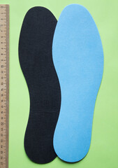 Insoles for shoes with ruler on green background. Top view.