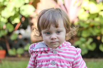 Close Up Portrait of a little 18 Month Old Girl with  Big Blue Eyes and Curly Hair, a girl Playing Outside, Funny Face Expression, Happy baby