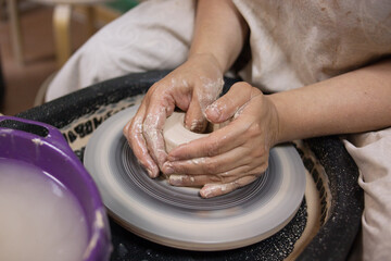 Hands creating pottery in class