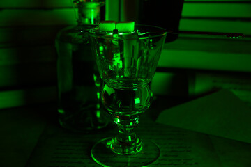 View on isolated absinth glass and bottle in gloomy green night atmosphere 