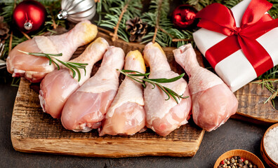 Christmas raw chicken legs on a stone background with spruce and new year toys 