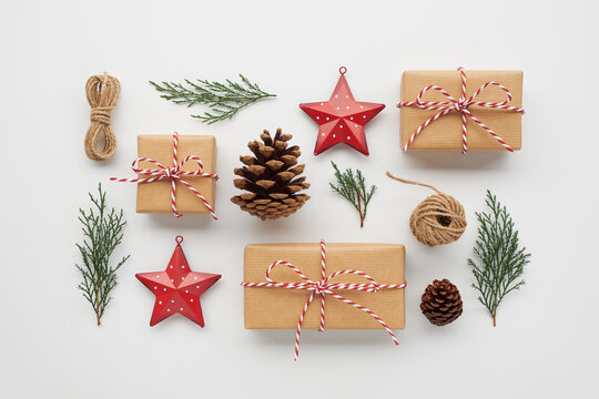Christmas composition with gift boxes wrapped in craft paper, pine cones, conifer branches, decorative toys on white background