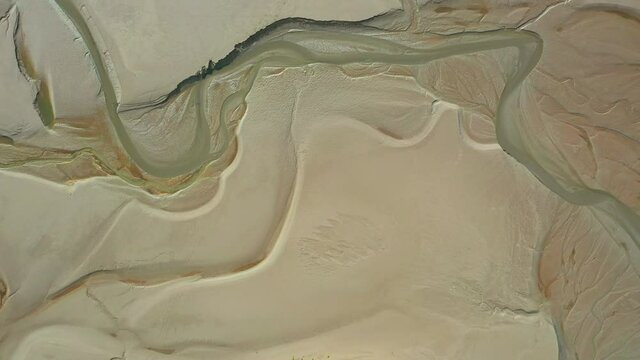 Aerial top down view over the sand on a costal bay, showing the contour pattens at low tide.