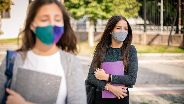 School child wearing face mask during corona virus and flu outbreak.Girls going back to school after covid-19 quarantine. Group of kids in masks for corona virus prevention.